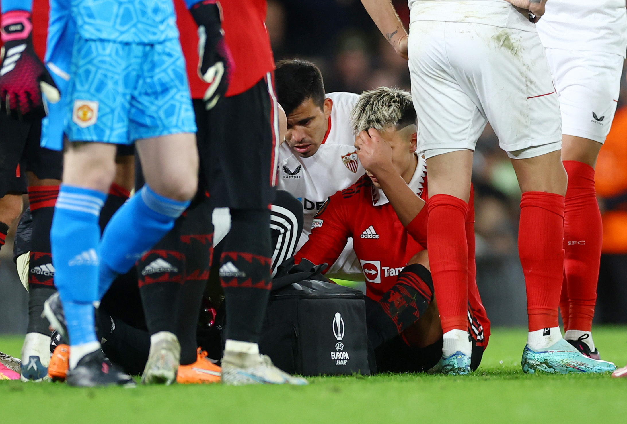 Soccer Football - Europa League - Quarter Final - First Leg - Manchester United v Sevilla - Old Trafford, Manchester, Britain - April 13, 2023  Manchester United's Lisandro Martinez receives medical attention after sustaining an injury as Sevilla's Marcos Acuna looks on Action Images via Reuters