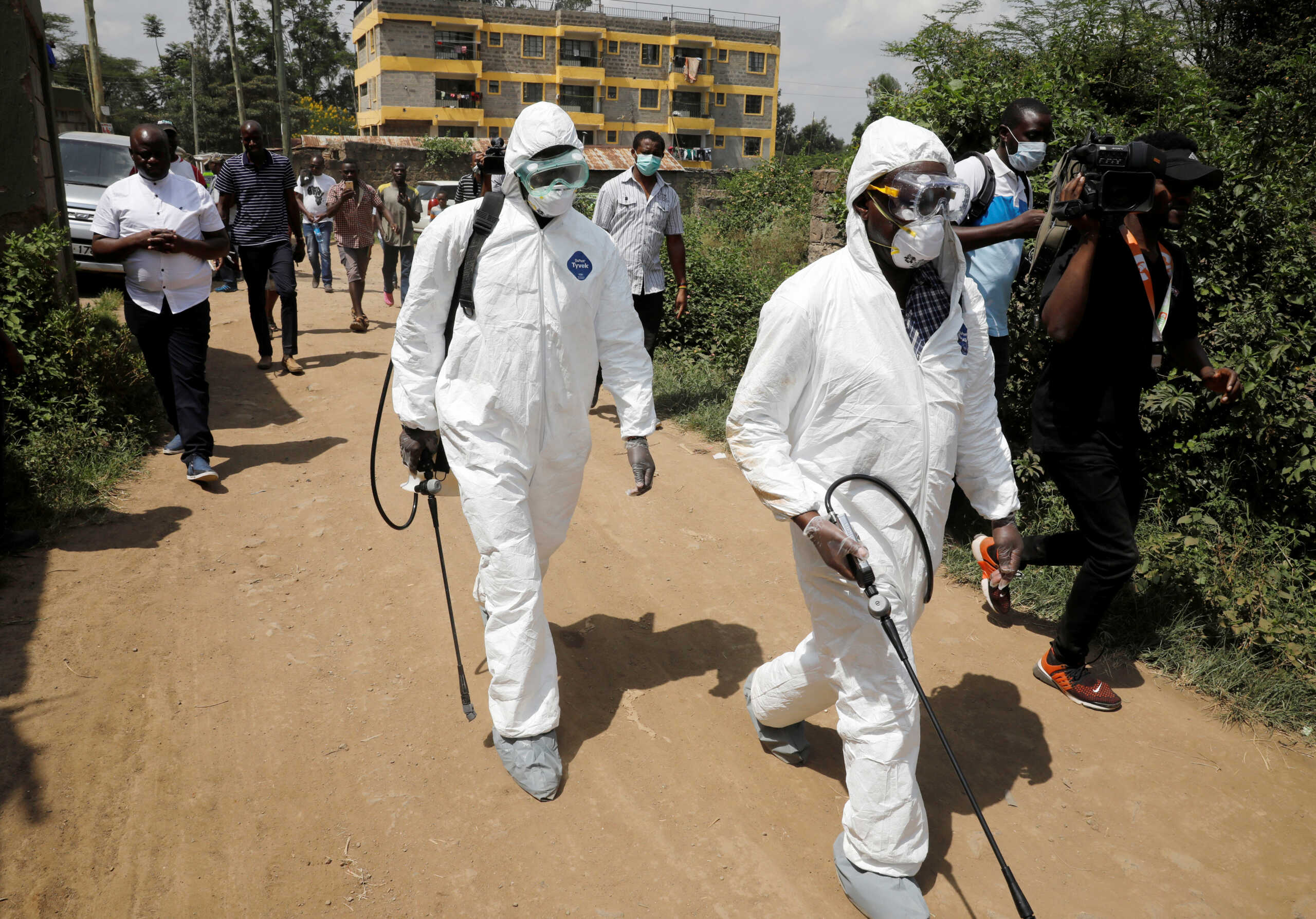 Kenyan health workers dressed in protective suits walk after disinfecting the residence where Kenya's first confirmed coronavirus patient was staying, in the town of Rongai near Nairobi, Kenya March 14, 2020. REUTERS