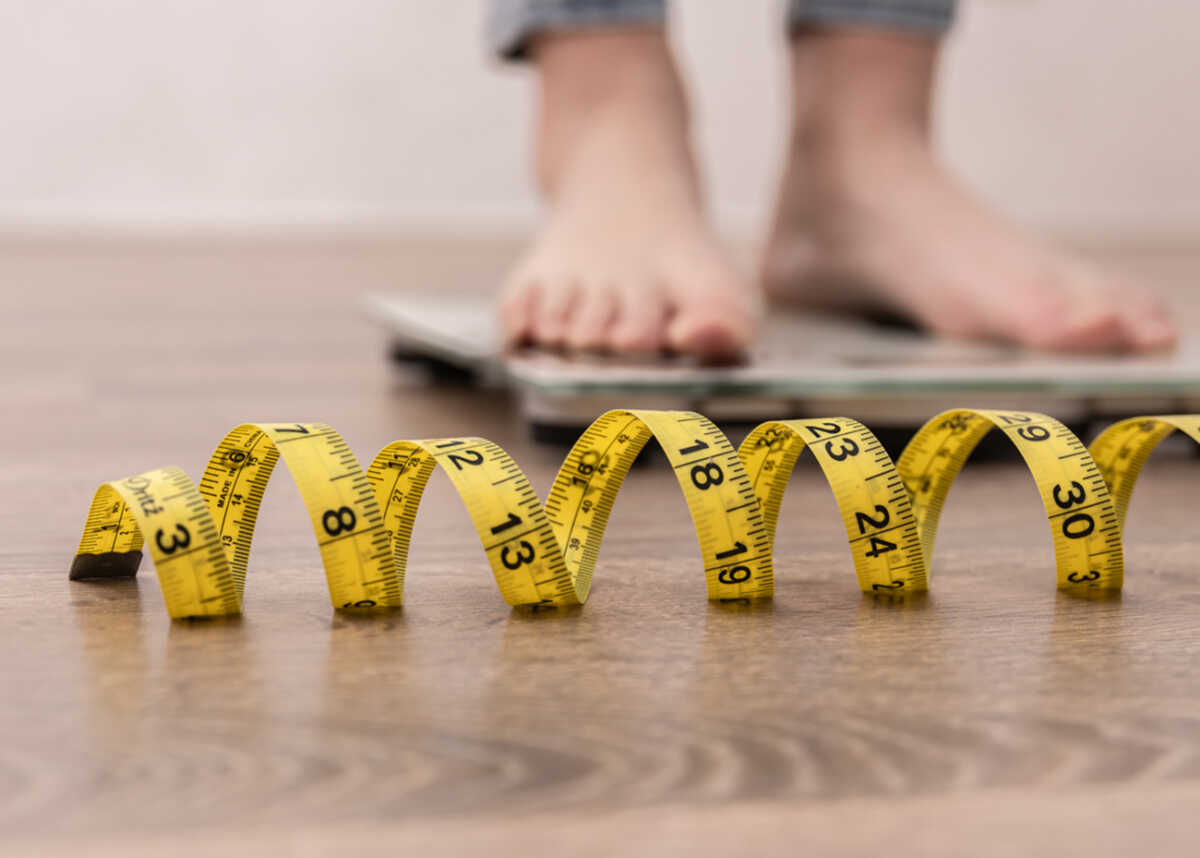Women's legs on the scales, close-up of a measuring tape, the concept of losing weight, healthy lifestyle.