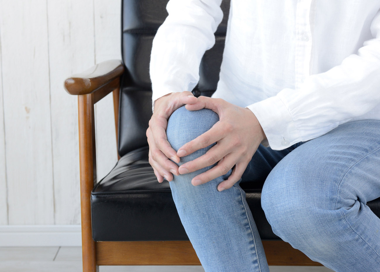 Woman holding painful knee in living room