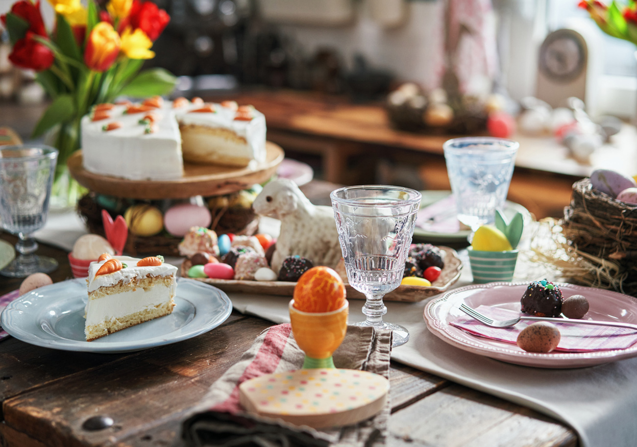 Colorful Decorated Easter Table with Easter Eggs, Flowers and Easter Cake