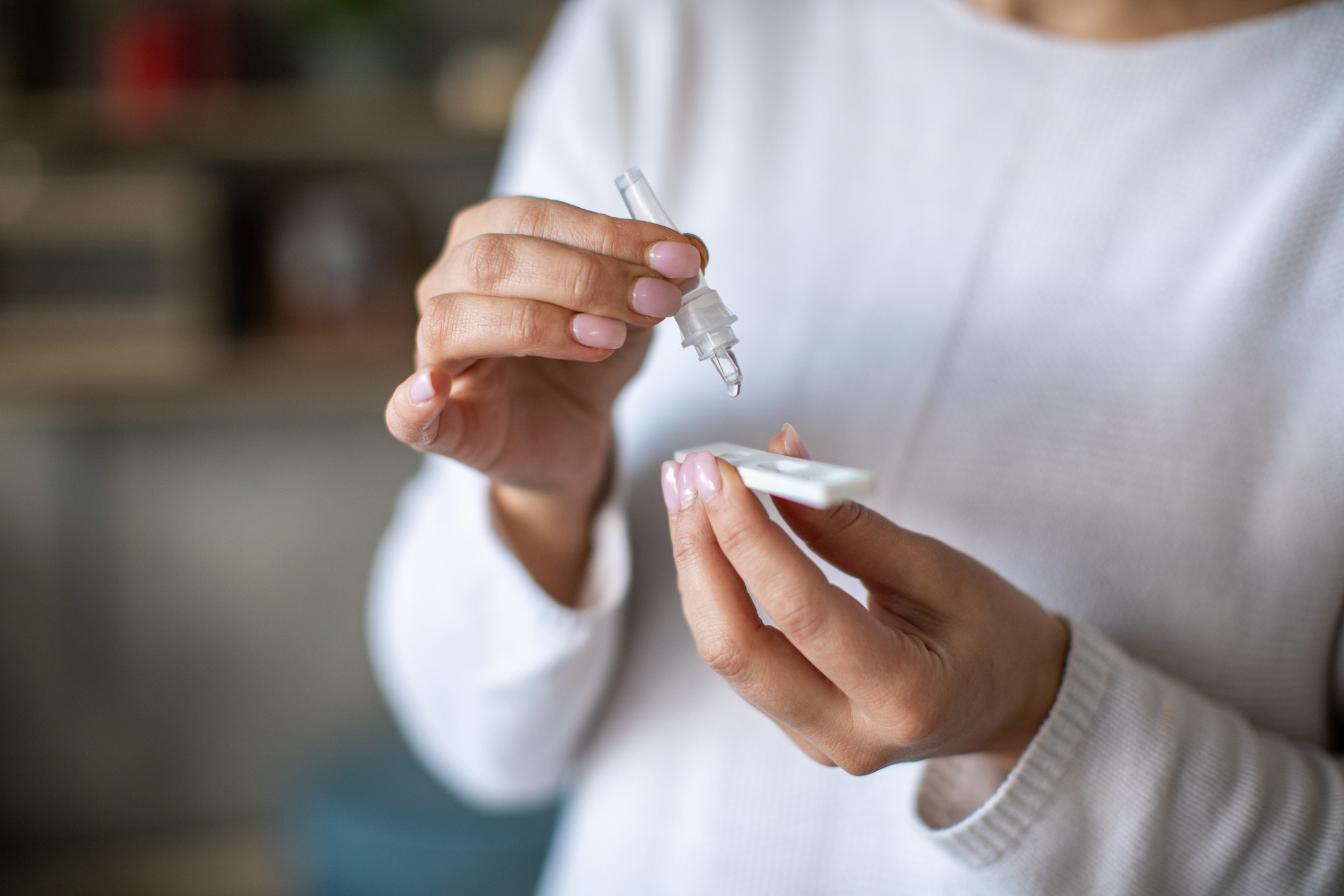 Unrecognizable woman drop nasal sample into rapid antigen test for coronavirus check.