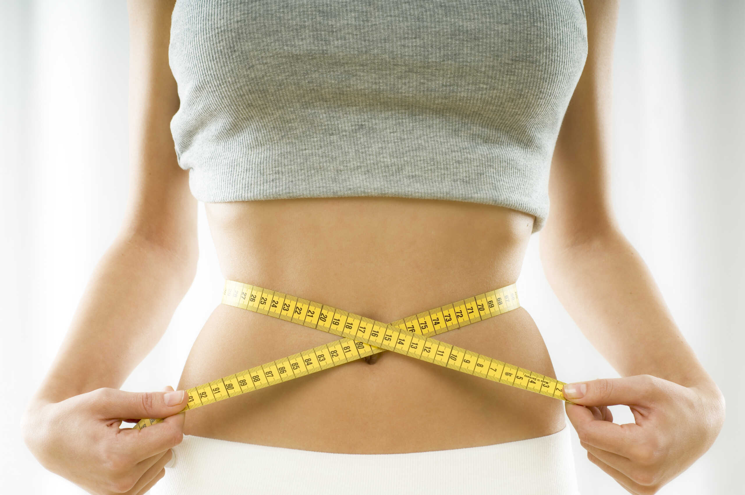 mid section view of a woman measuring her waist