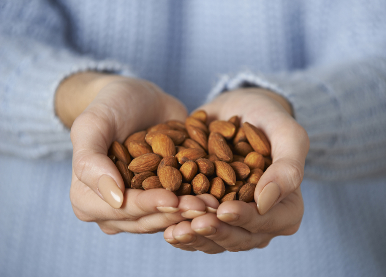Close Up Of Woman Holding Handful Of Almonds