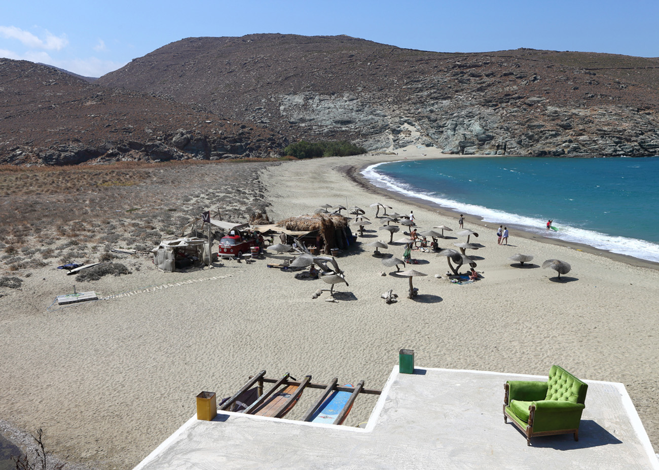 Tinos, Greece - August 31, 2016 : Relaxed atmosphere on the beach of Kolympithra where surfers rest in the shade of the parasols after a surfing session