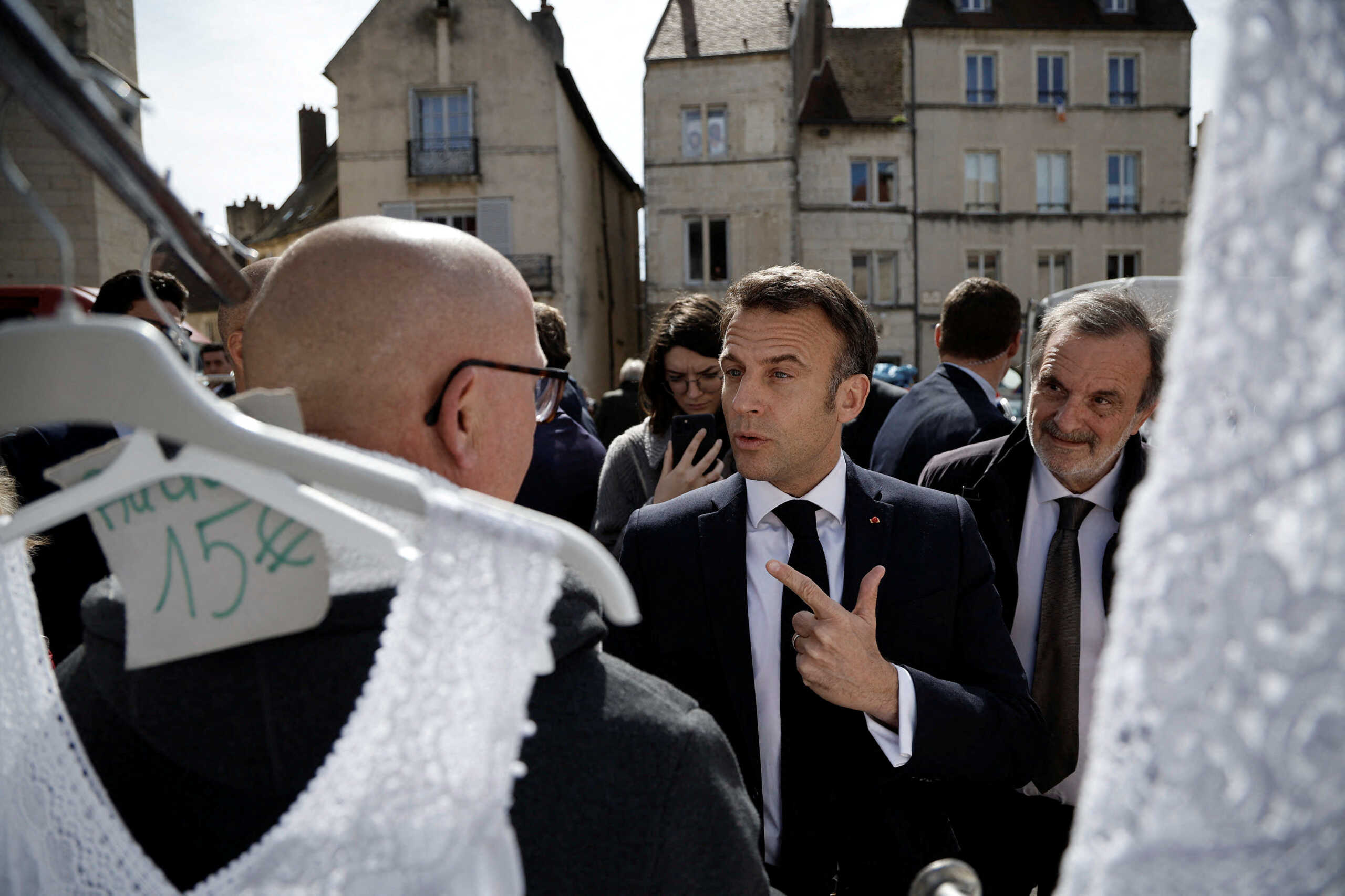 French President Emmanuel Macron (C) greets people at the Dole market before a visit to 'Chateau de Joux' for a ceremony marking the 175th anniversary of the abolition of slavery in France, in La Cluse-et-Mijoux, near Besancon, eastern France, 27 April 2023. CHRISTOPHE PETIT-TESSON