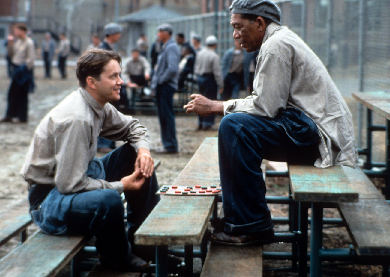 Tim Robbins and Morgan Freeman sitting outside on the benches playing checkers and talking in a scene from the film 'The Shawshank Redemption', 1994. (Photo by Castle Rock Entertainment