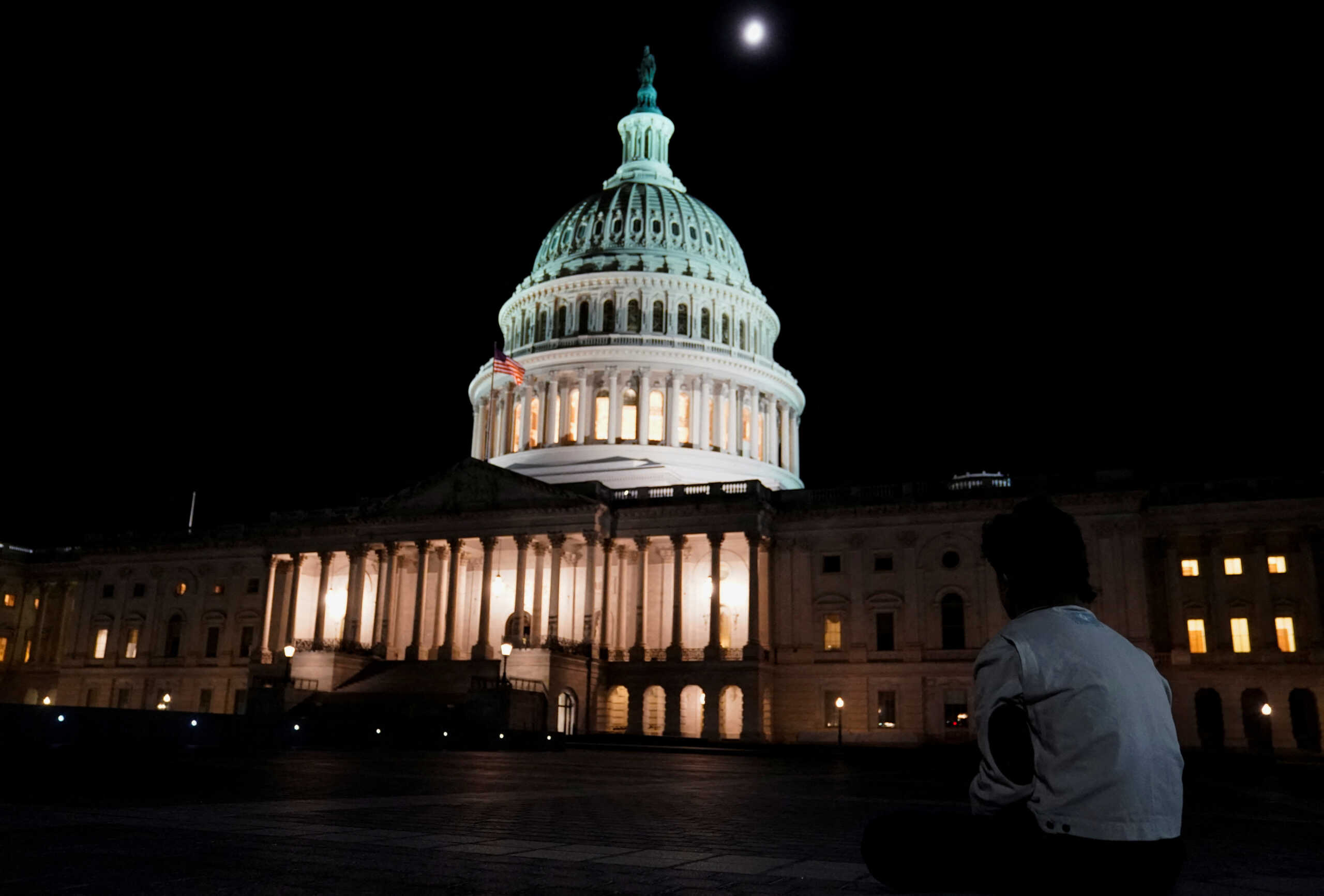 A person sits outside the U.S. Capitol after U.S. House Speaker Kevin McCarthy (R-CA) reached a tentative deal with President Joe Biden to raise the United States' debt ceiling and avoid a catastrophic default, in Washington, U.S. May 27, 2023. REUTERS