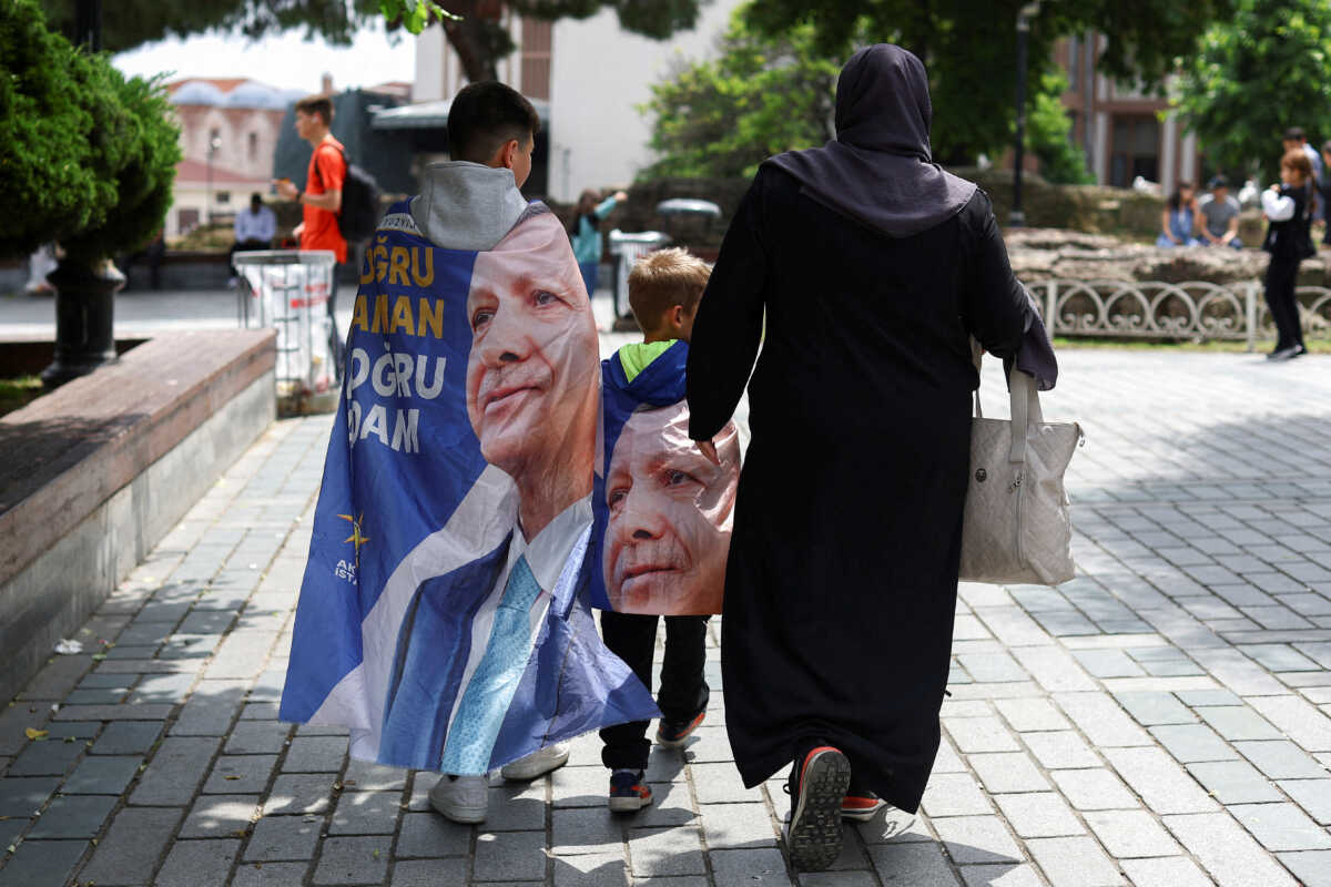 People walk while draped in banners featuring Turkish President Tayyip Erdogan, after he was declared the winner in the second round of the presidential election, in Istanbul, Turkey, May 29, 2023. REUTERS