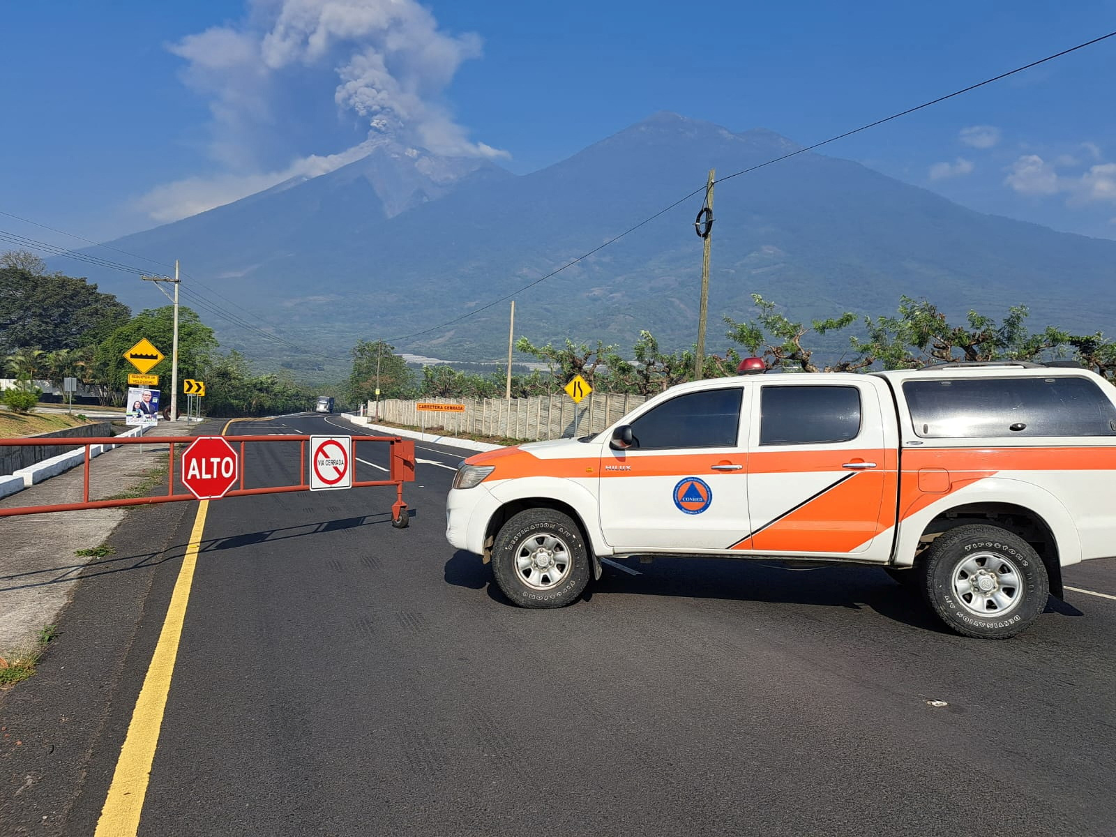 A vehicle of the Guatemala's disaster management agency (CONRED) blocks a road as the Fuego volcano spews a column of steam during an increase of its activity, in Alotenango, Guatemala May 4, 2023. Guatemala Coordinadora Nacional para la Reduccion de Desastres (CONRED)