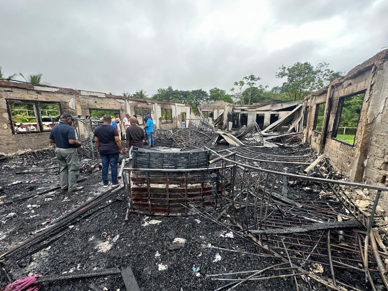 People stand inside the remains of a burnt secondary school dormitory after several children, most of them from indigenous communities, died after a fire gutted the building overnight, in Mahdia, Guyana in this handout image obtained by Reuters on 22 May, 2023. Guyana Presidency