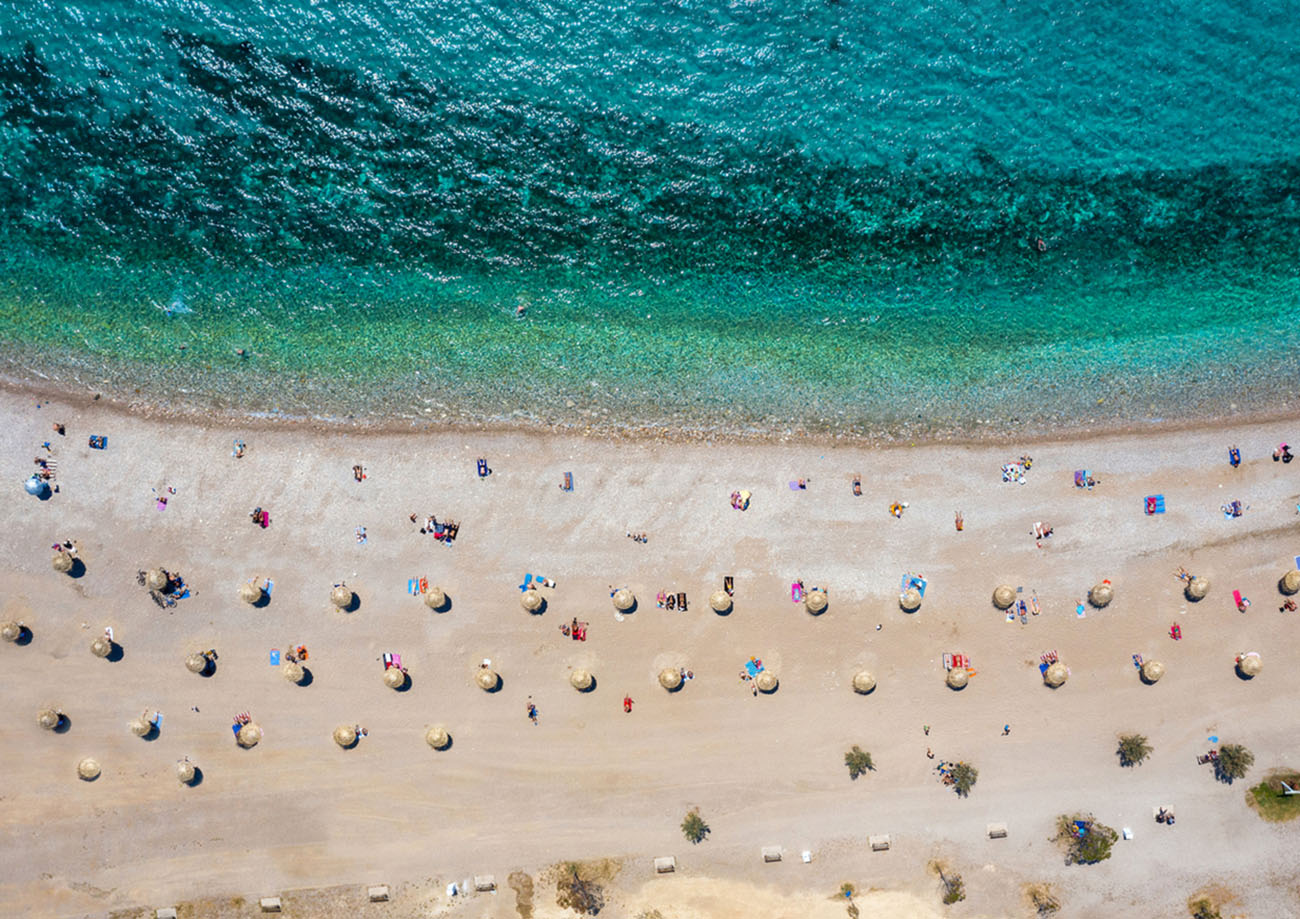 Aerial top down view to the beach of Glyfada district, south Athens Riviera, Greece, with umbrellas set away from each other under Corona social distancing measures