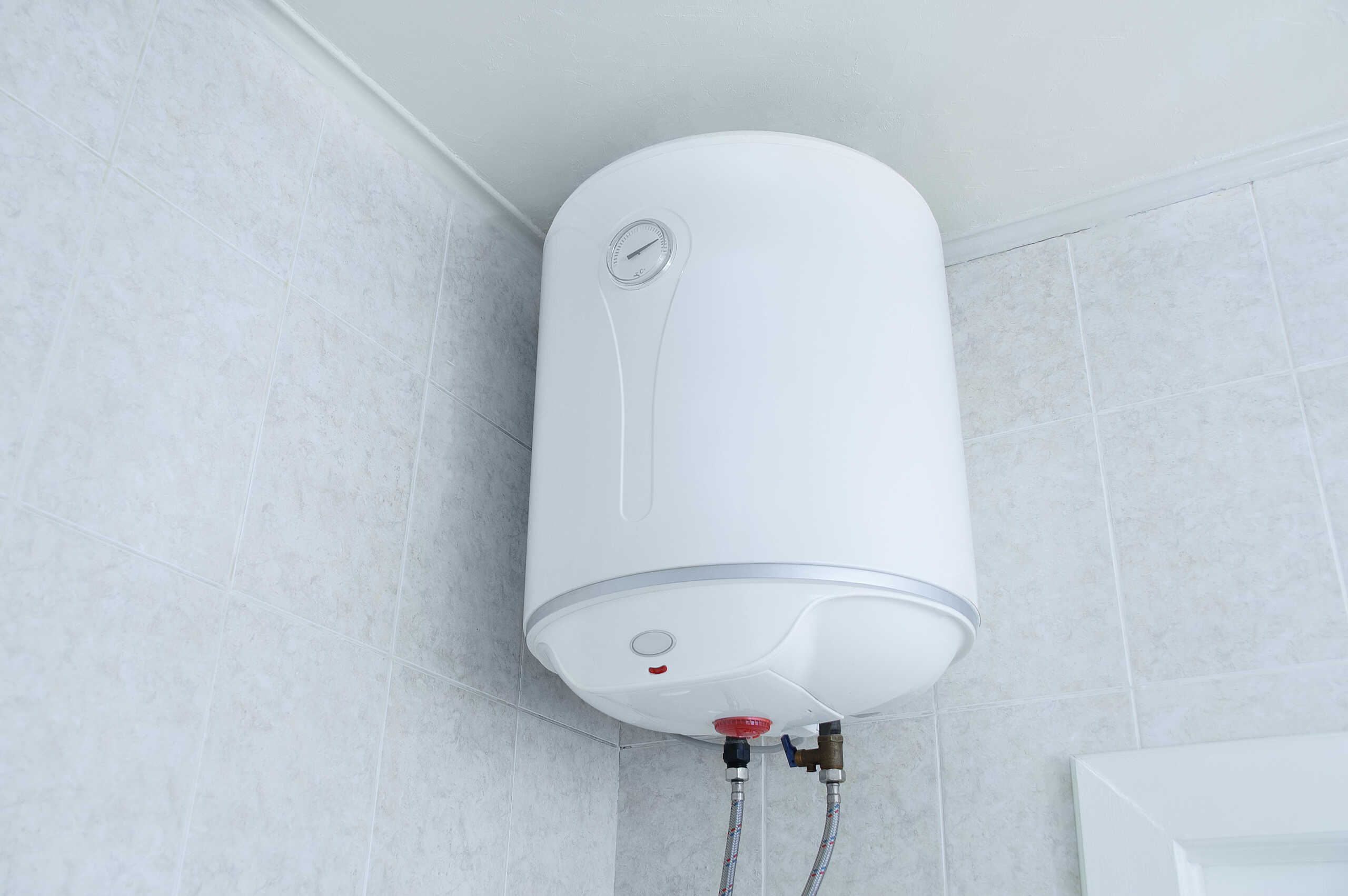 White electric water heater boiler on the wall in the bathroom.