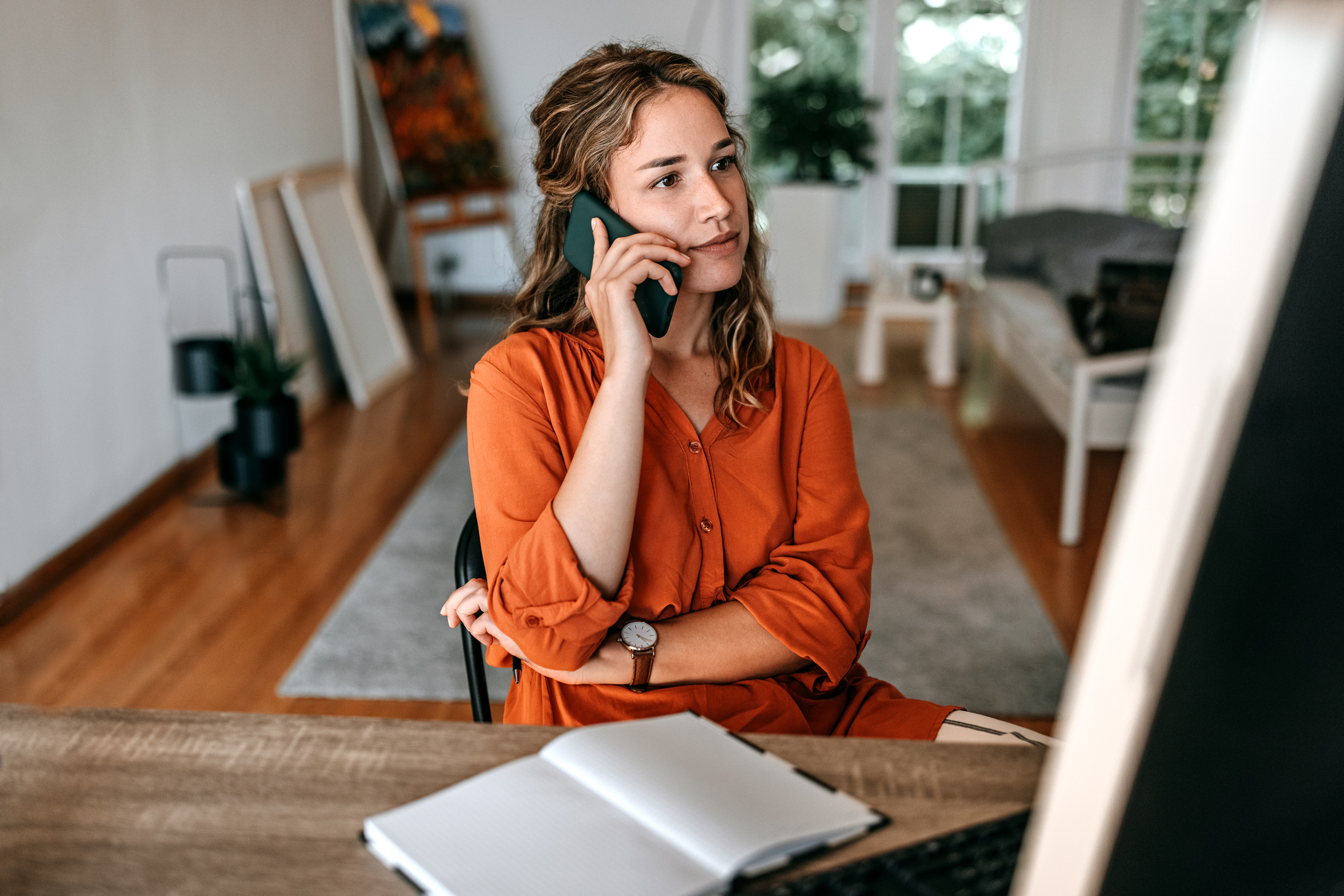 Young woman talking on smart phone while working at home office