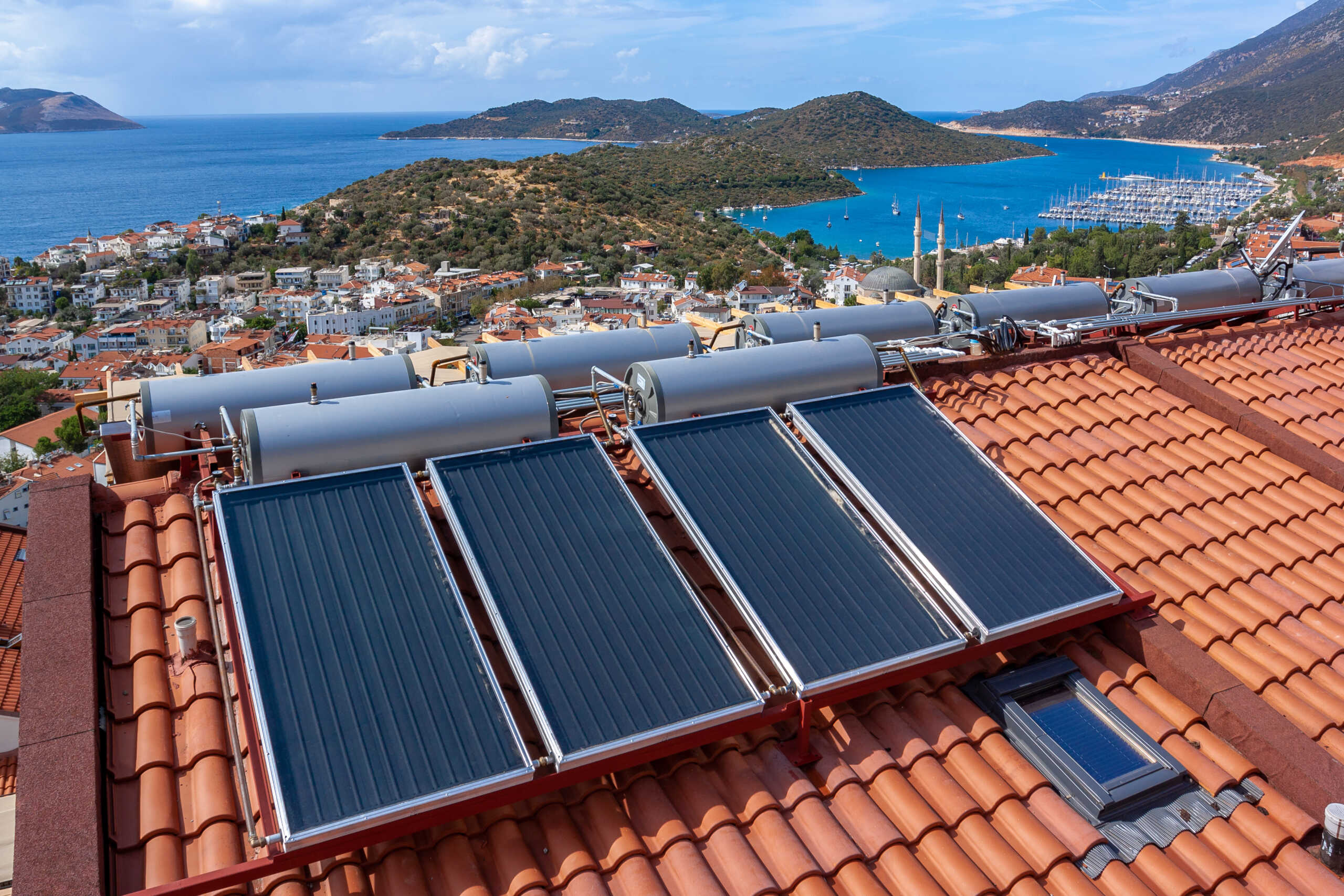 Solar water heater installed on tile roof of house for economical heating of water. A lot of large water tanks.