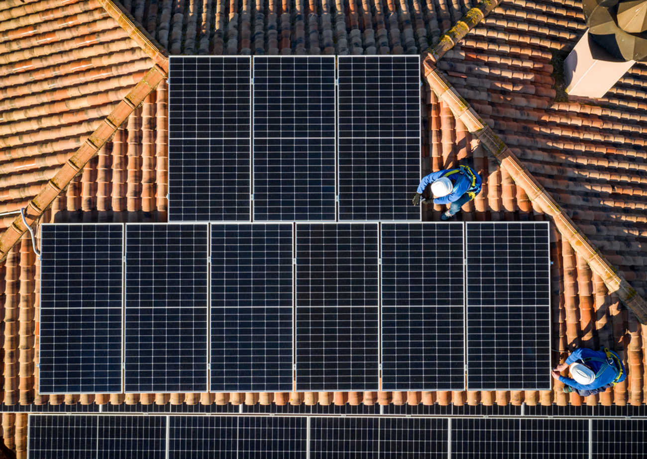 aerial view of Two workers installing solar panels on a house roof