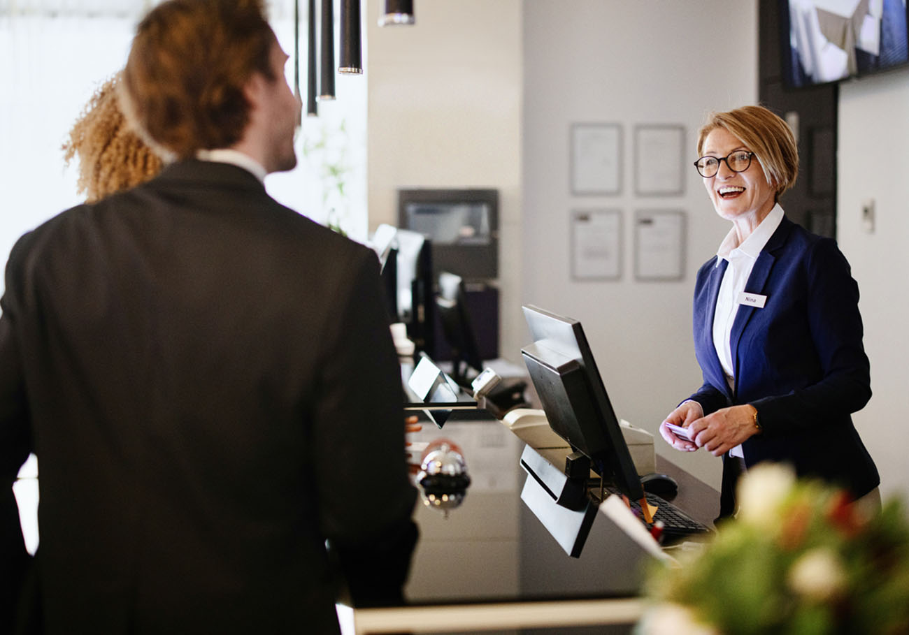 Female hotel receptionist helping a business couple guests in checking in process. Hotel receptionist assisting guests for checking in