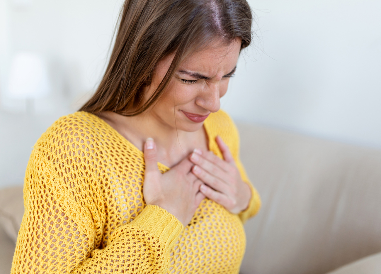 Young woman having chestpain,Acute pain, possible heart attack.Effect of stress and unhealthy lifestyle concept.