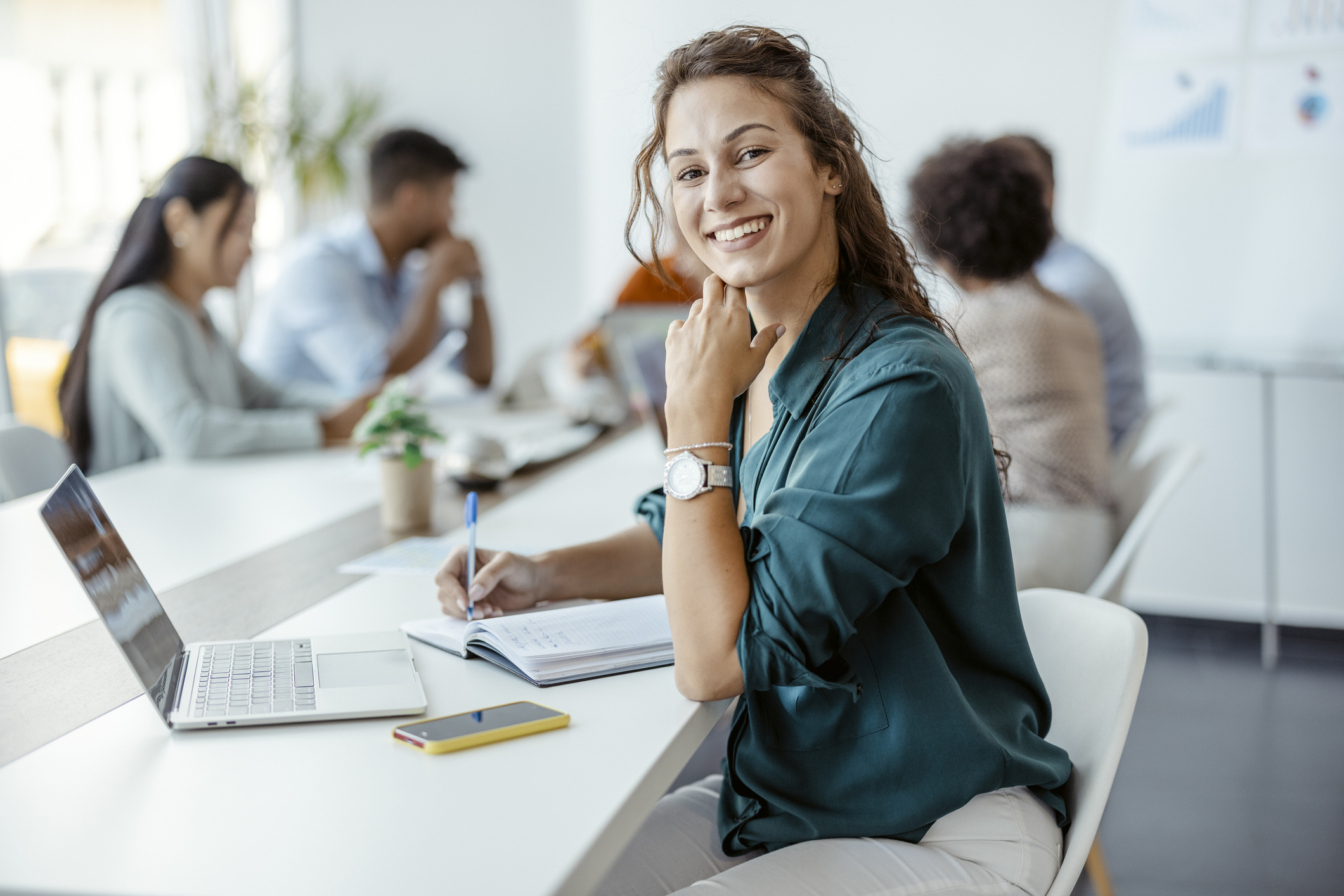 Female Employee Smiling in the Office, With Her Colleagues in Background. Shallow Focus