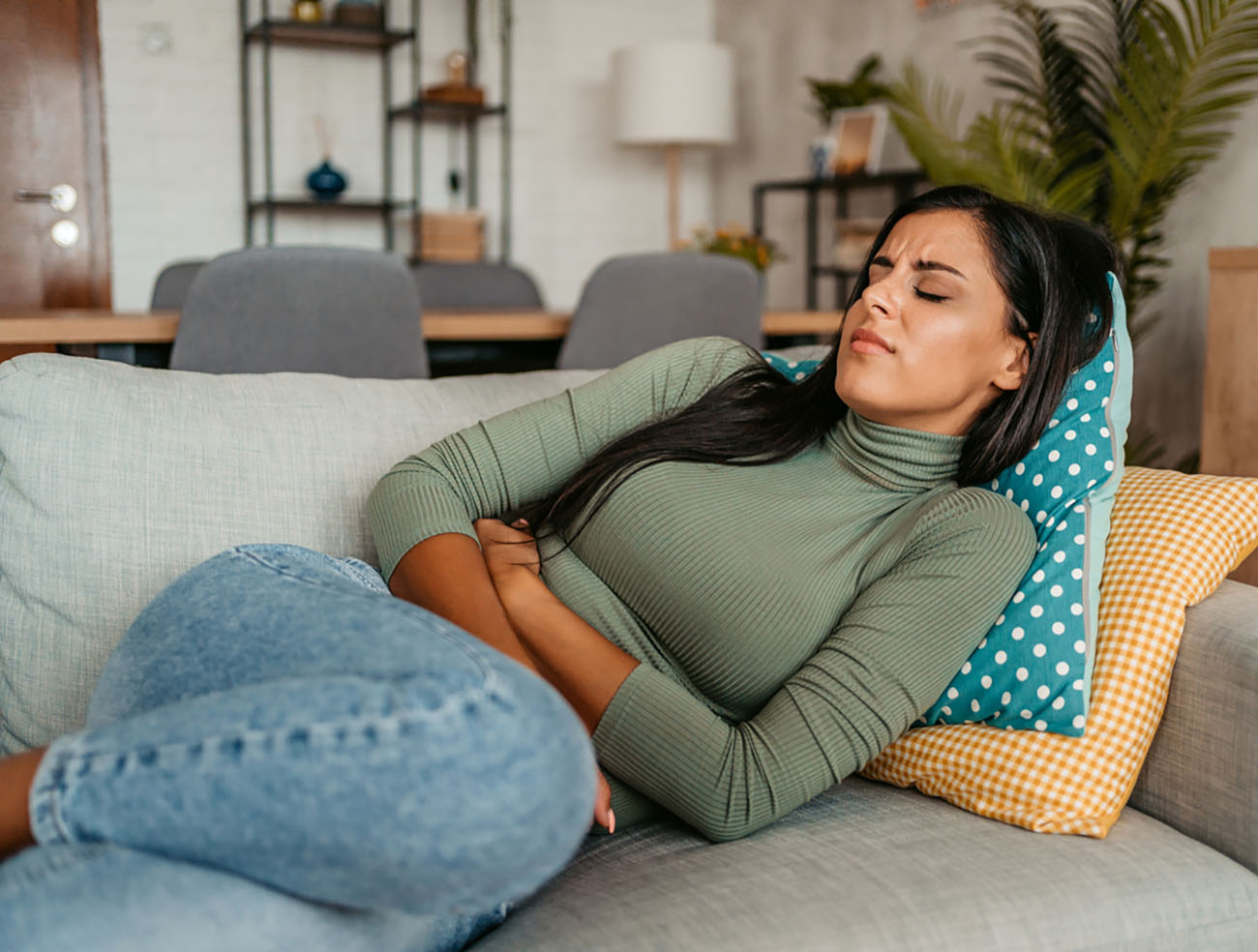 Young woman lying on the sofa and having period cramps.