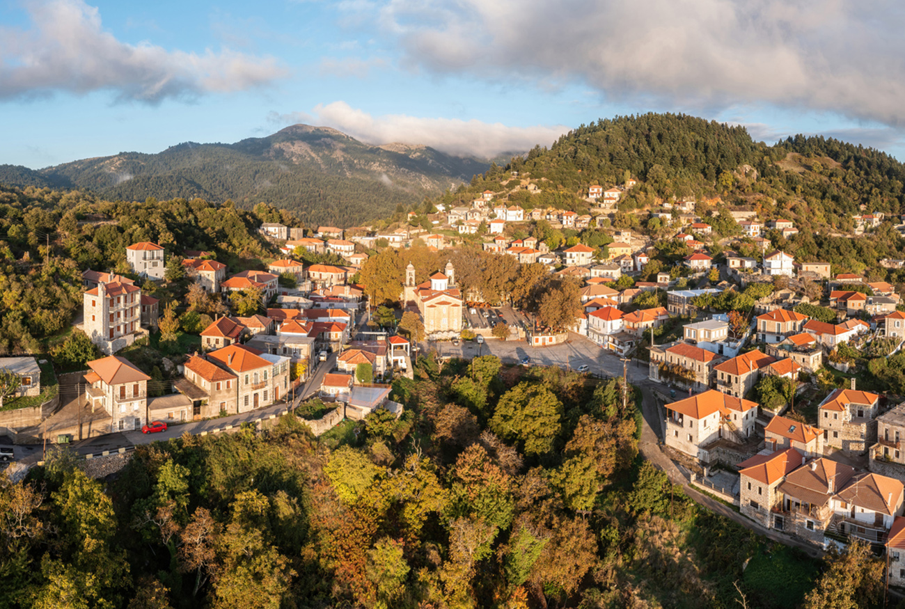 Greece village Kosmas on mountain Parnonas aerial drone view, Peloponnese. Traditional tile roof and stone wall buildings, cloudy blue sky, Autumn