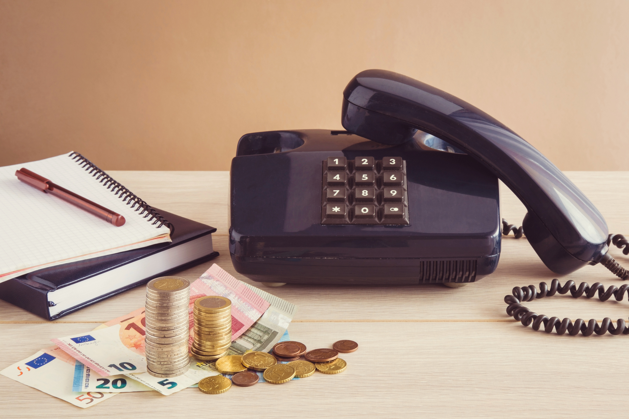 Old telephone on the table with notebooks and Euro money.