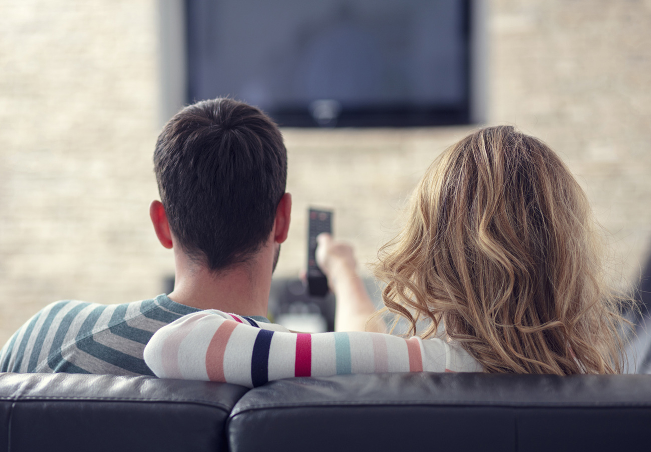 Happy young couple relaxing and watching TV at home