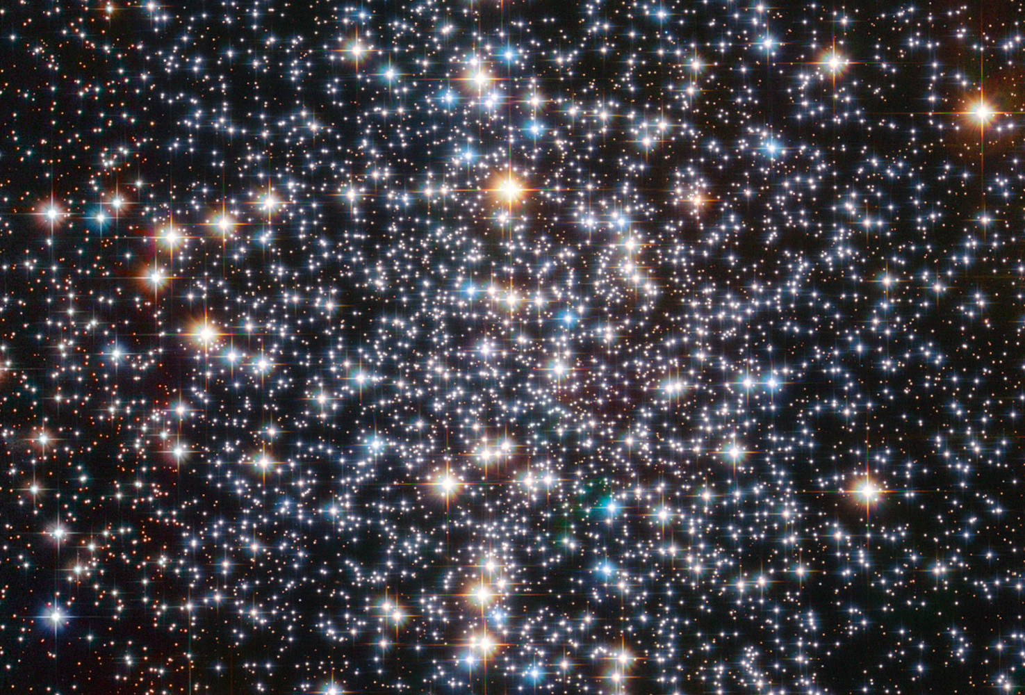 A Hubble Space Telescope image of the globular star cluster, Messier 4. The cluster is a dense collection of several hundred thousand stars. Astronomers suspect that an intermediate-mass black hole, weighing as much as 800 times the mass of our Sun, is lurking, unseen, at its core. [Image description: Thousands of bright points of light on a black background fill the field of view. They appear somewhat more concentrated near the centre of the image. They have a variety of colours, with the most prominent stars appearing blue or yellow-orange. The brighter stars also display four diffraction spikes.]