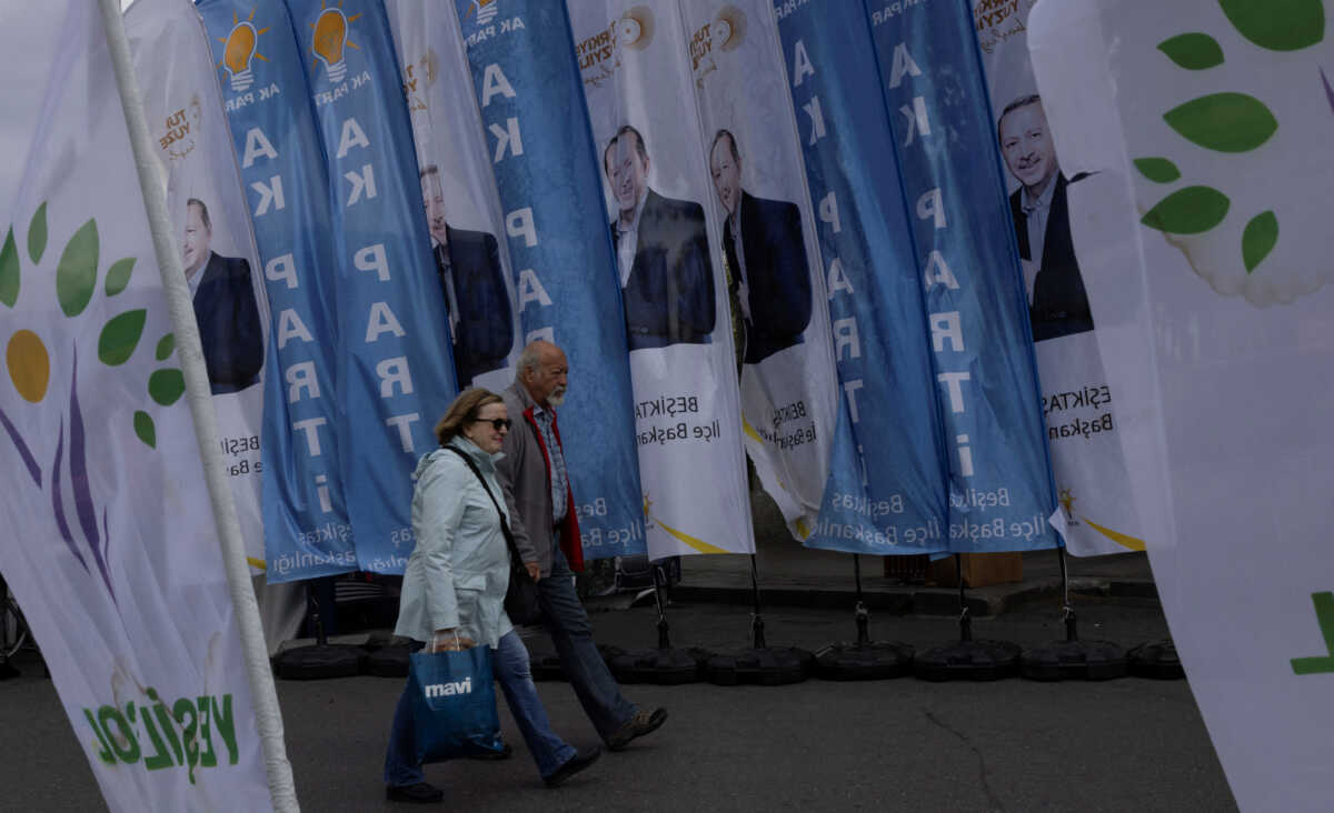People pass by portraits of Turkish President Tayyip Erdogan, AK Party and Green Left Party flags ahead of the May 14 presidential and parliamentary elections in Istanbul, Turkey May 9, 2023. REUTERS