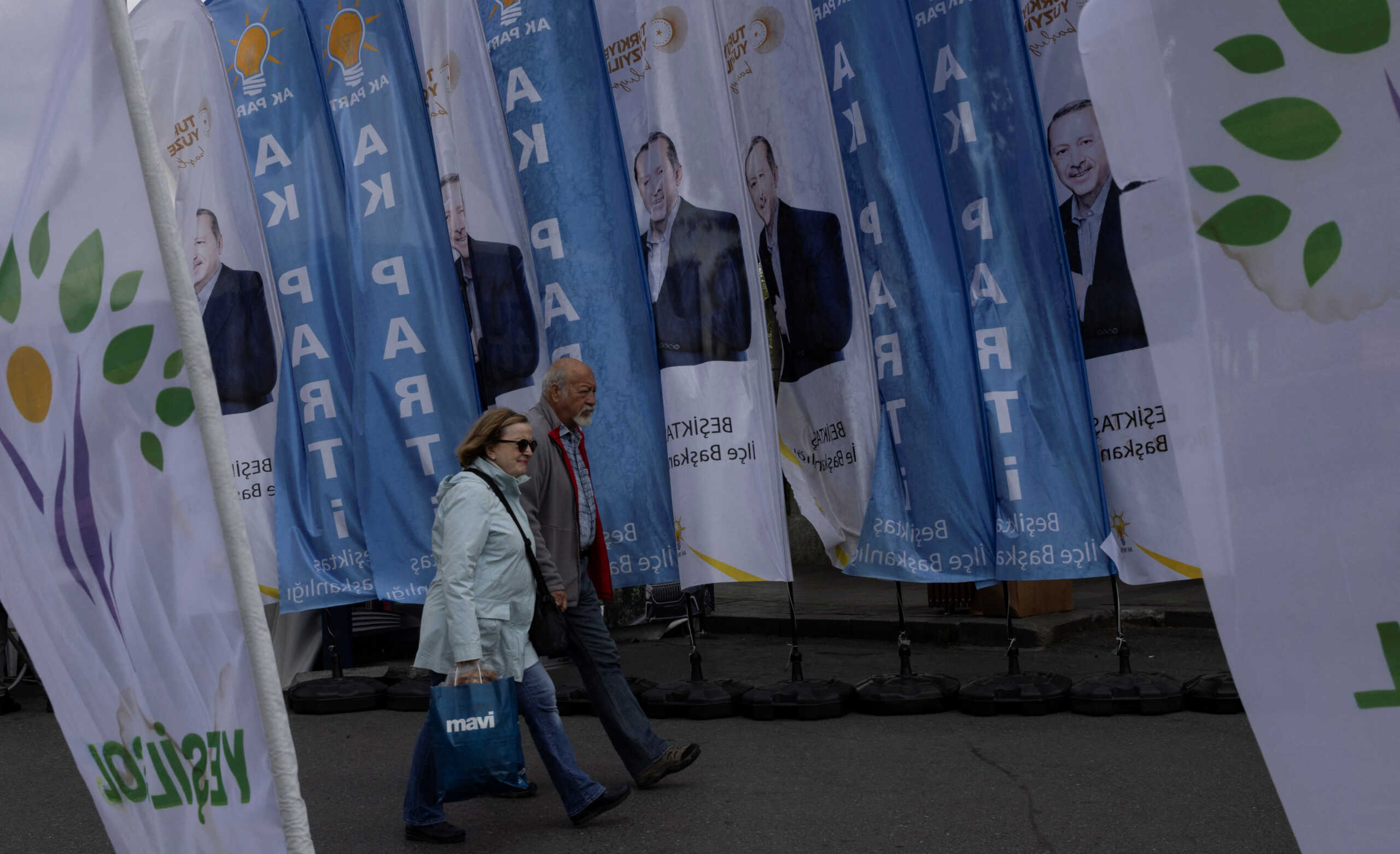 People pass by portraits of Turkish President Tayyip Erdogan, AK Party and Green Left Party flags ahead of the May 14 presidential and parliamentary elections in Istanbul, Turkey May 9, 2023. REUTERS
