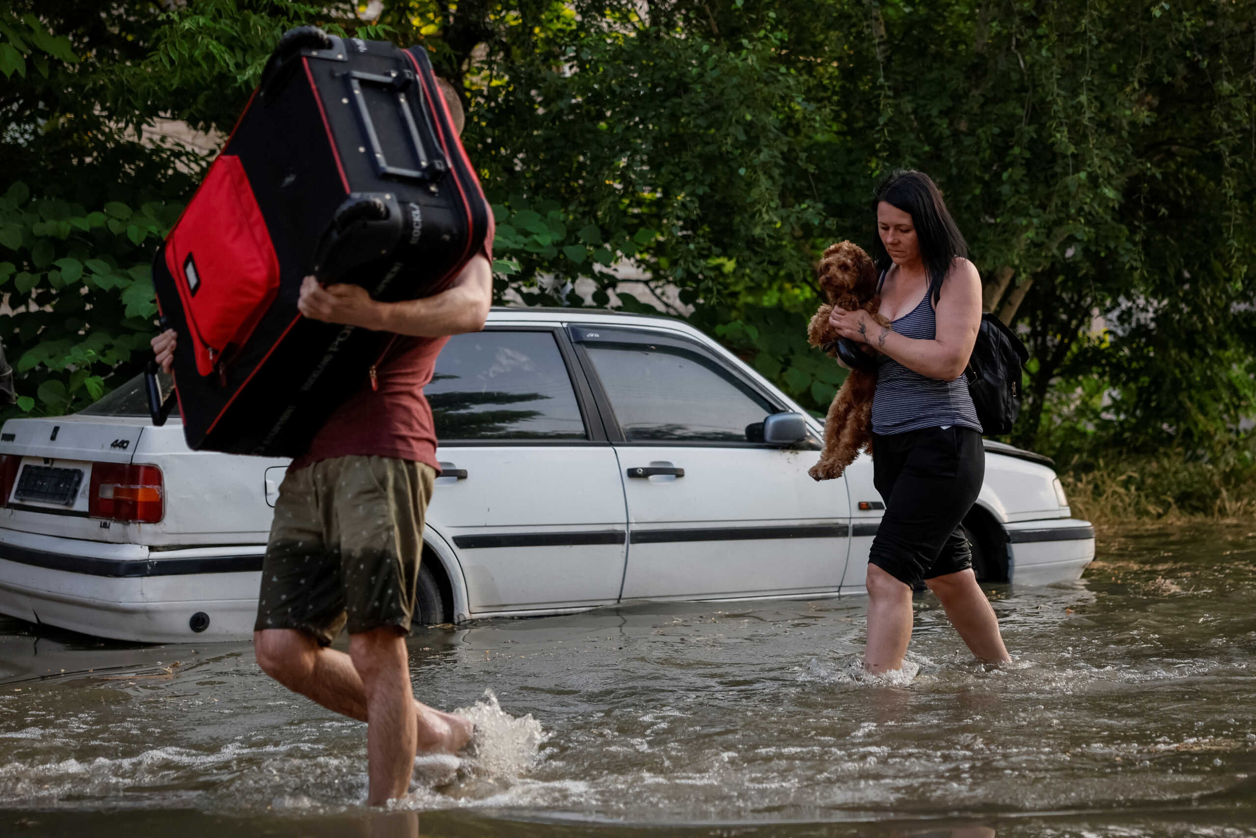 Local residents carry their personal belongings on a flooded street, after the Nova Kakhovka dam breached, amid Russia's attack on Ukraine, in Kherson, Ukraine June 6, 2023. REUTERS