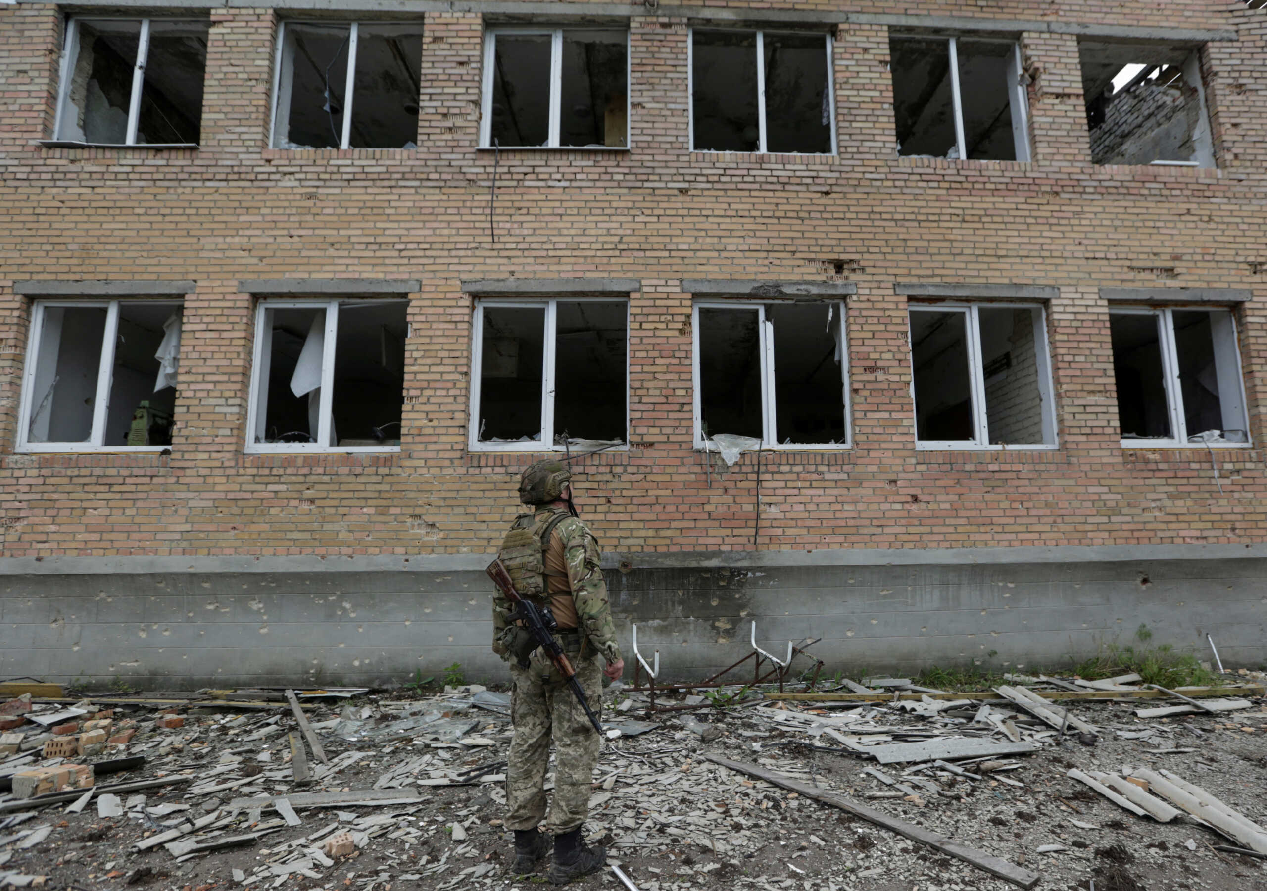 A Ukrainian serviceman stands next to a damaged building, amid Russia's attack on Ukraine, in the village near a frontline in Donetsk region, Ukraine June 1, 2023. REUTERS
