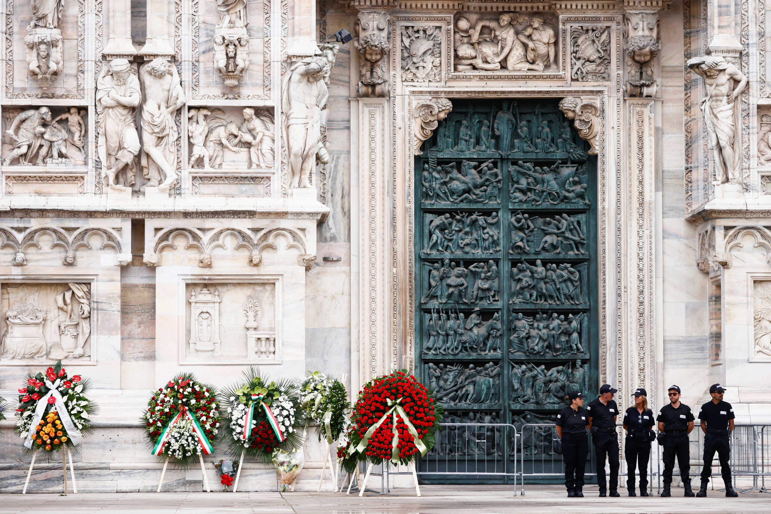 Security personnel stand near the garlands for the funeral of former Italian Prime Minister Silvio Berlusconi, in front of the Duomo Cathedral, in Milan, Italy June 14, 2023. REUTERS