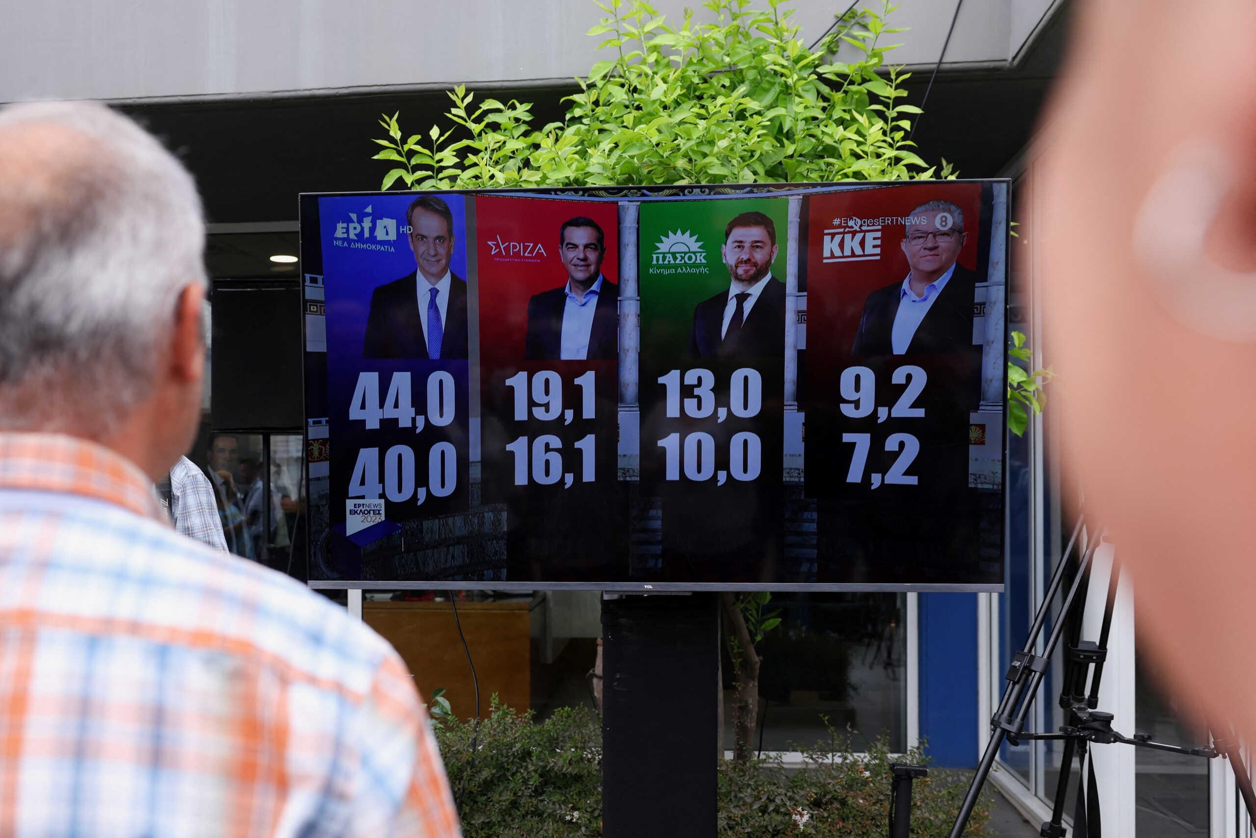 People look at a screen displaying first exit poll on the day of the general election, in Athens, Greece, June 25, 2023. REUTERS