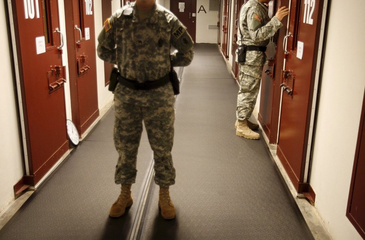 epa01143245 A U.S. soldier stands guard as another does a cell check in Camp Delta 5 on U.S. Naval Base, Guantanamo Bay, Cuba on 09 October 2007. The U.S. Government currently maintains custody of approximately 340 enemy combatants in the Global War on Terrorism at Guantanamo Bay, Cuba.  EPA