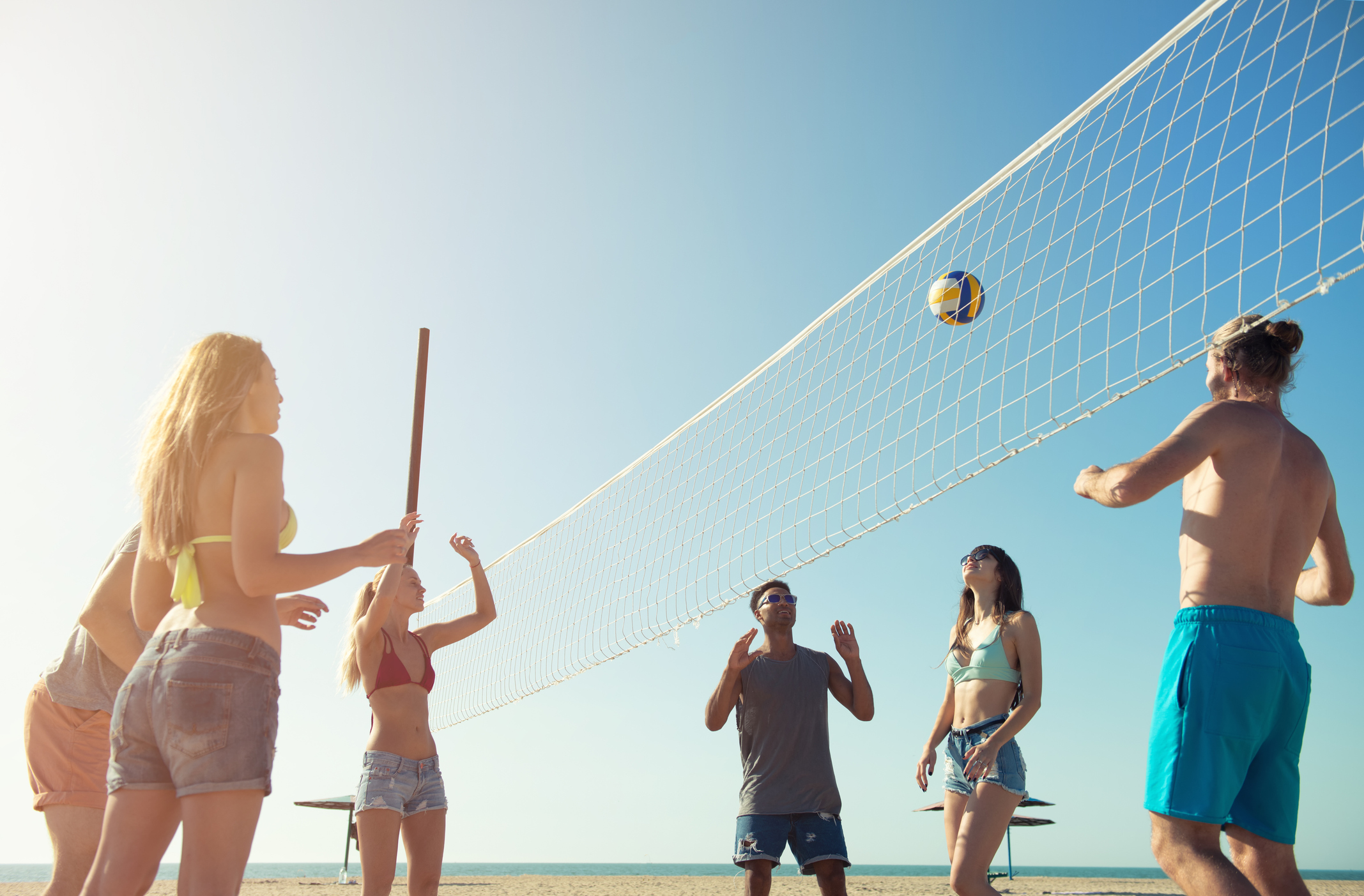Group of happy friends playing at beach volley at the beach