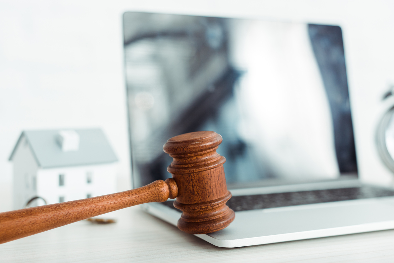 selective focus of wooden gavel near laptop and model of house