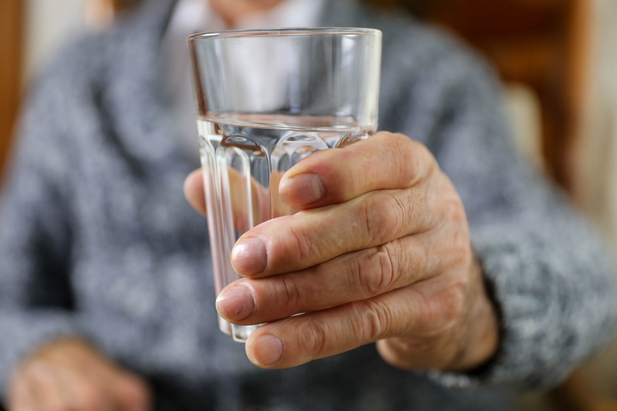 A pensioner with a glass of water in his hand