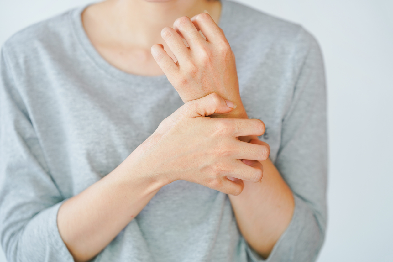 A woman scratching her arm, experiencing an allergic reaction or being stung by an insect. Skin disease concept.