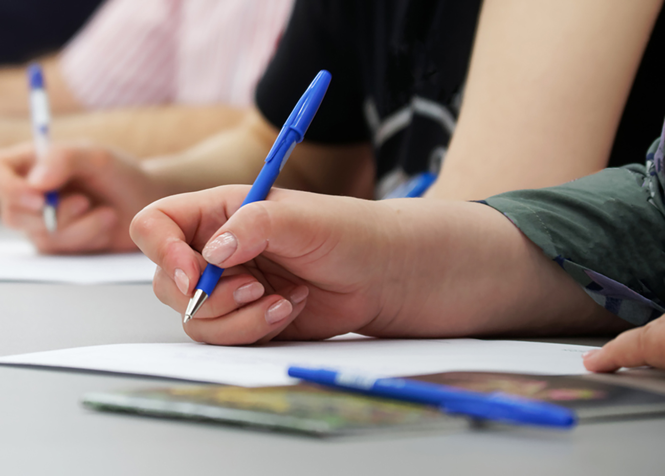 The girls write with fountain pens on sheets of paper. Concept for college exam, filling out forms and questionnaires. Web banner. Close-up. Without a face