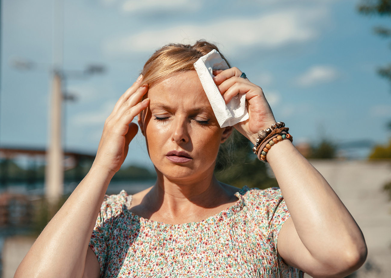 Woman feeling bad pain, heat, woman with heatstroke. Mature Female under sunshine suffering from Headache. Person holds paper tissue on head