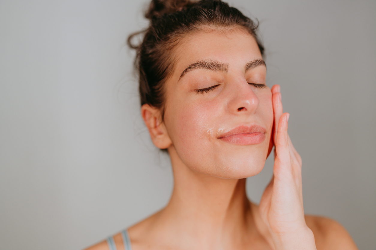 Photo of a girl applying face serum on her skin as a part of her beauty routine