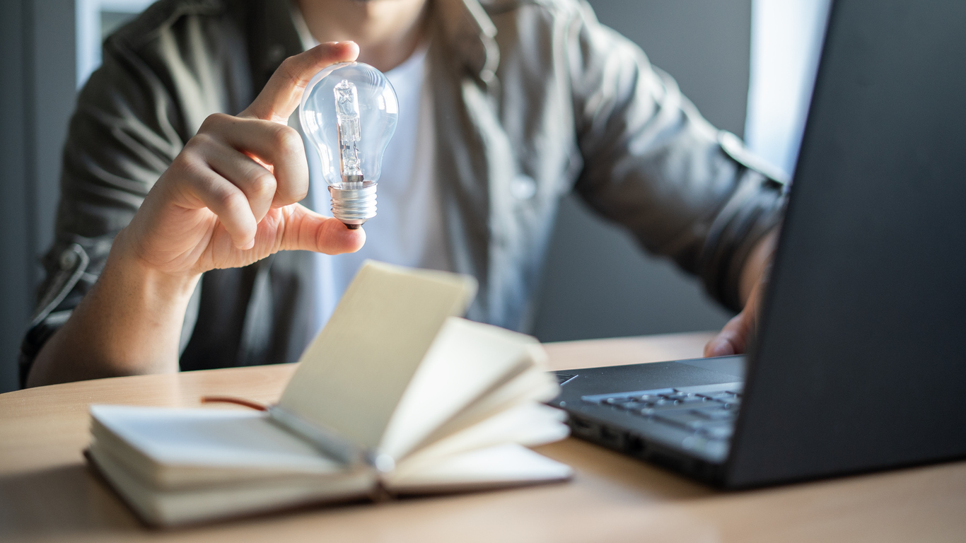 Businessman holding light bulb while working with laptop