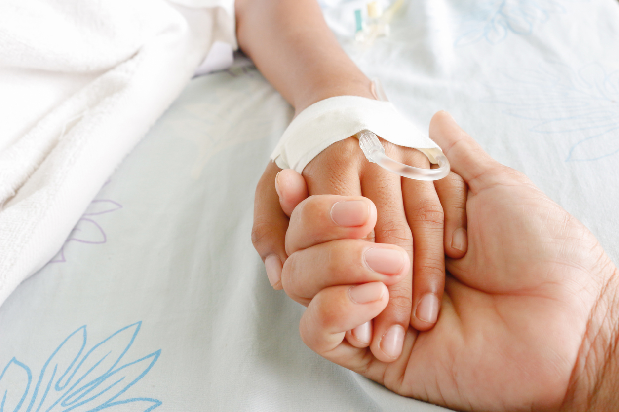 mother holding child's hand who fever patients have IV tube.