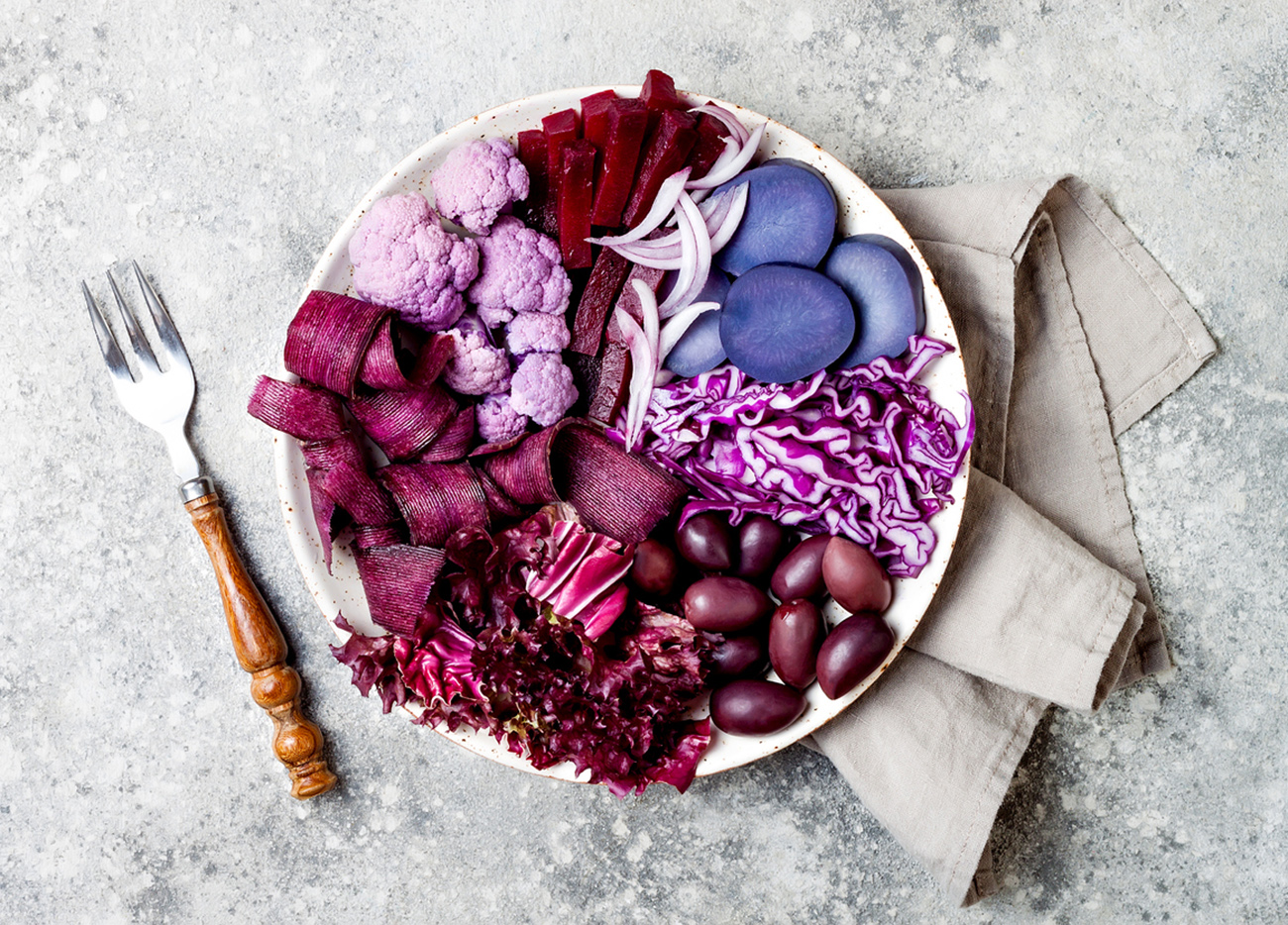 Purple Buddha bowl with spiral carrots, cauliflower, beet, onion, potato, shredded red cabbage, radicchio salad, kalamata olives. Vegan detox veggie bowl