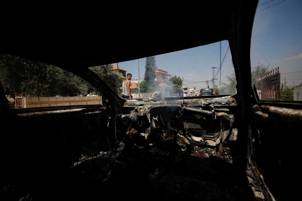 A Palestinian looks at a burned car, after an attack by Israeli settlers, near Ramallah, in the Israeli-occupied West Bank, June 21, 2023. REUTERS