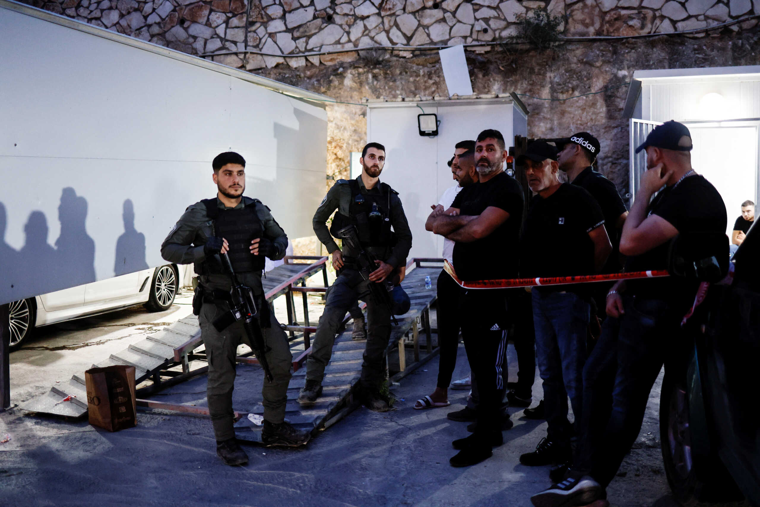 Workers and security personnel walk around a car wash where five men were killed in one of the deadliest crime-related shootings in Israel's recent history, in a suburb of the northern city of Nazareth, Israel June 8, 2023. REUTERS