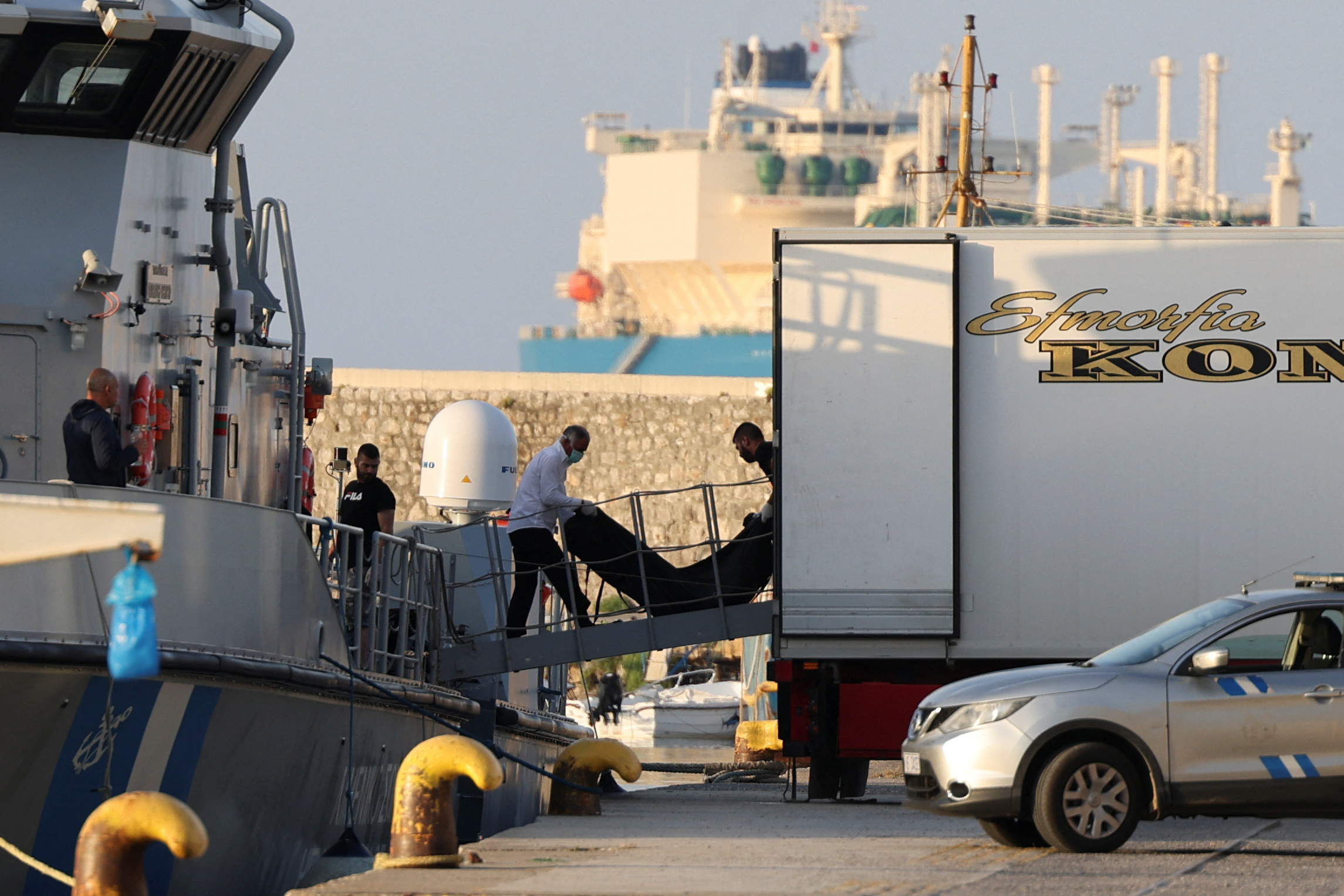 Men transfer body bags carrying migrants who died after their boat capsized in the open sea off Greece, onboard a Hellenic Coast Guard vessel at the port of Kalamata, Greece, June 15, 2023. REUTERS