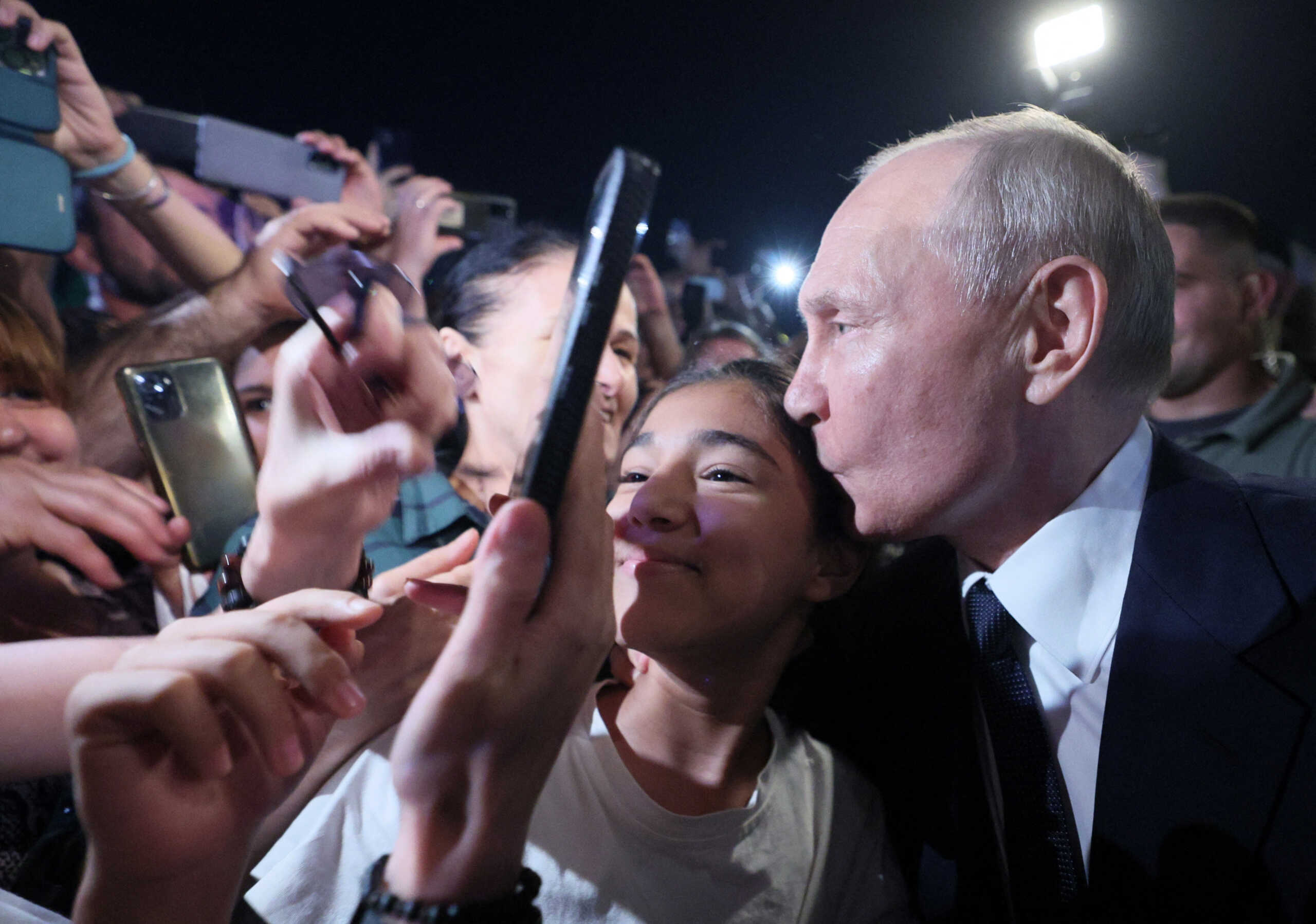 Russian President Vladimir Putin kisses a participant of a meeting in a street in Derbent in the southern region of Dagestan, Russia, June 28, 2023. Sputnik