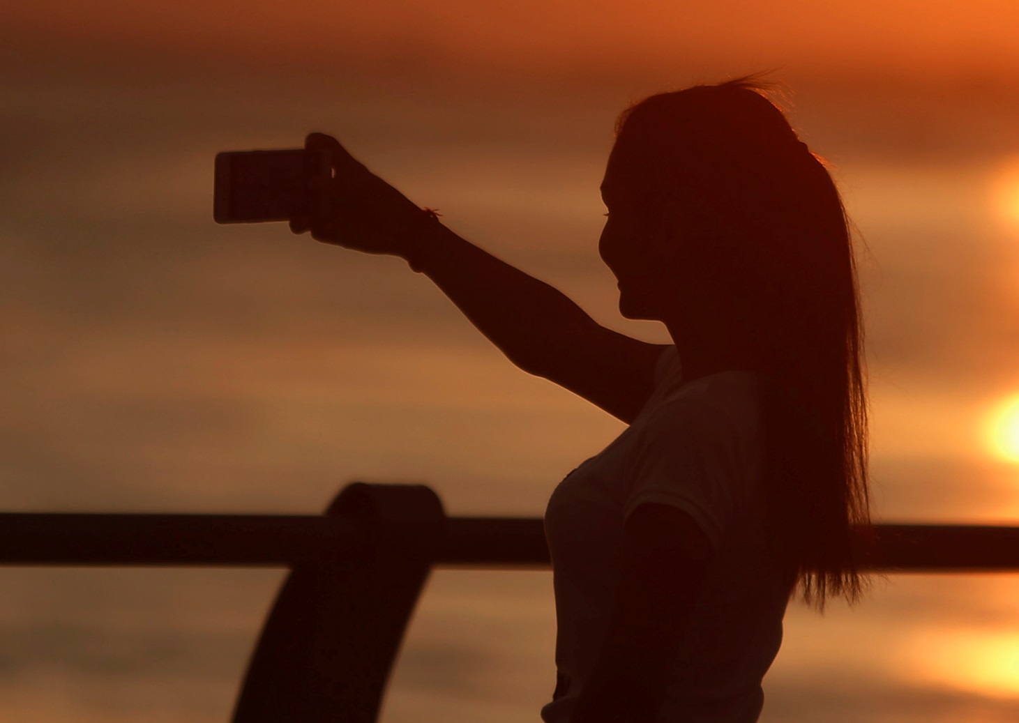 A woman uses her smartphone to take a selfie as the sun rises on the Tonle Sap river in Phnom Penh, Cambodia November 20, 2018. REUTERS